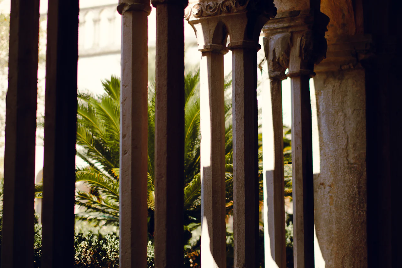 Stone colonnade opening onto a palm tree